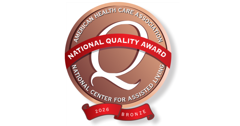 A circular badge with a bronze gradient background features a large white letter 